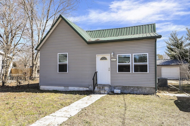 view of front of house featuring metal roof, a front yard, and fence