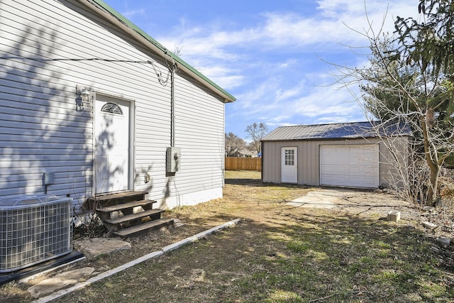 view of side of property featuring central air condition unit, an outbuilding, fence, entry steps, and a garage