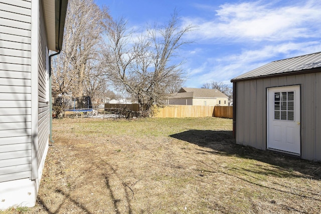 view of yard with fence, a trampoline, an outdoor structure, and a shed
