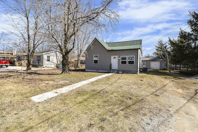 view of property exterior with driveway, metal roof, and a lawn