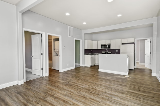 kitchen with freestanding refrigerator, white cabinetry, wood finished floors, stainless steel microwave, and visible vents
