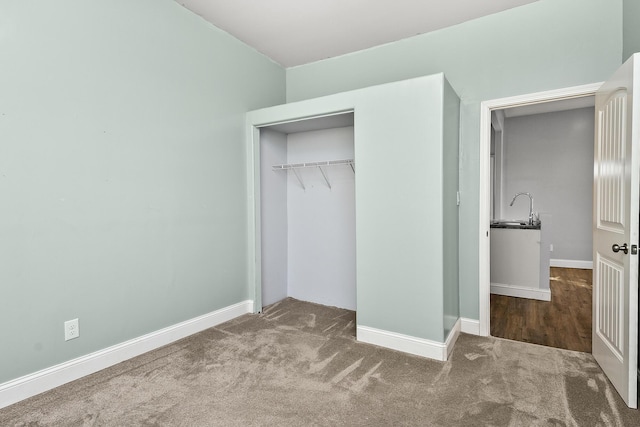 unfurnished bedroom featuring a closet, carpet floors, a sink, and baseboards