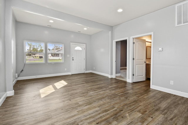 foyer with baseboards, visible vents, and wood finished floors