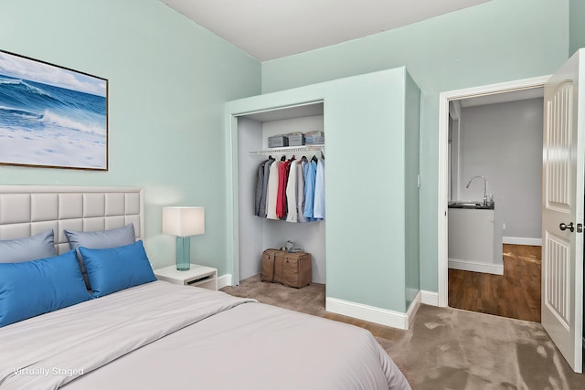 bedroom with baseboards, carpet, a closet, and a sink