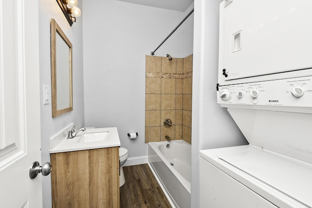 bathroom with vanity, shower / bath combination, toilet, stacked washing maching and dryer, and wood finished floors