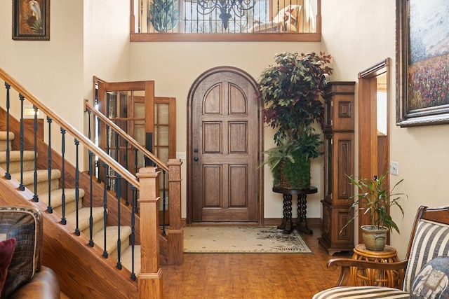 foyer featuring stairway, wood finished floors, and a towering ceiling