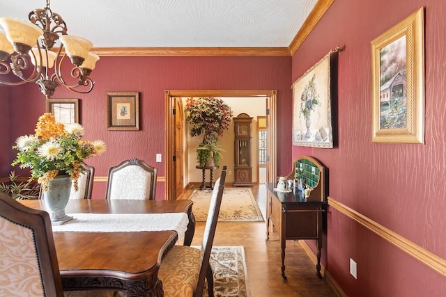 dining space with a chandelier, ornamental molding, wood finished floors, and baseboards