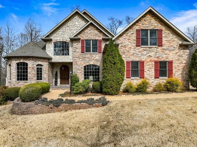 view of front of home featuring roof with shingles, a front yard, and brick siding