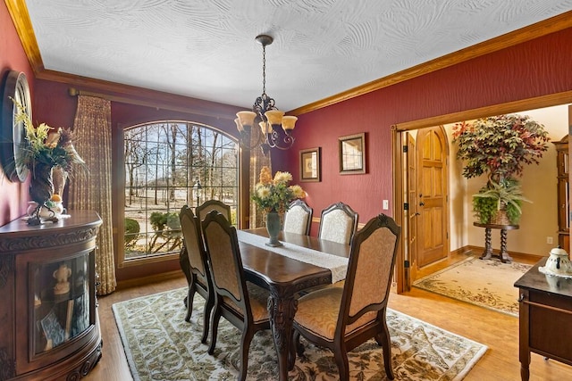 dining room with light wood-type flooring, a chandelier, and ornamental molding