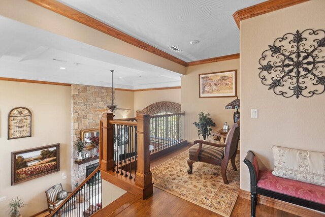 hallway featuring visible vents, crown molding, an upstairs landing, and wood finished floors