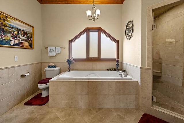 bathroom featuring toilet, tile patterned floors, a garden tub, a shower stall, and tile walls