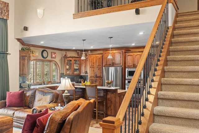 living area with a towering ceiling, stairway, crown molding, and recessed lighting