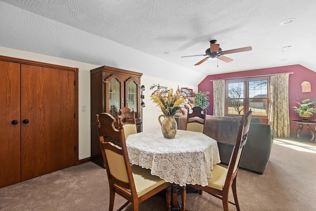 dining room featuring light carpet, vaulted ceiling, and a textured ceiling