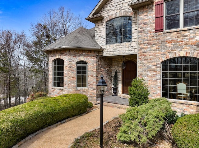 exterior space featuring brick siding and roof with shingles