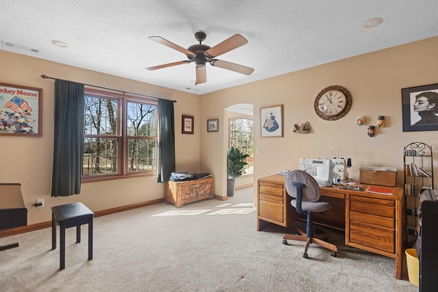 carpeted office space with a ceiling fan and baseboards