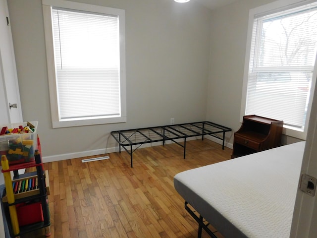 bedroom with baseboards, visible vents, and hardwood / wood-style floors