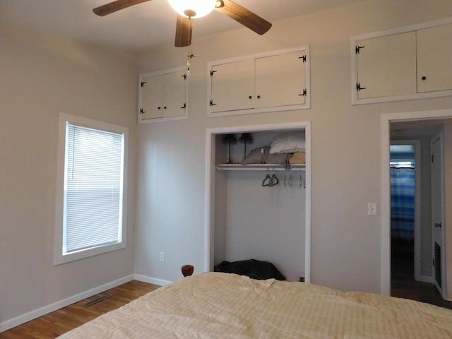 bedroom with a closet, visible vents, a ceiling fan, wood finished floors, and baseboards