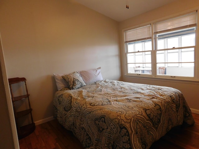 bedroom featuring lofted ceiling, baseboards, and wood finished floors