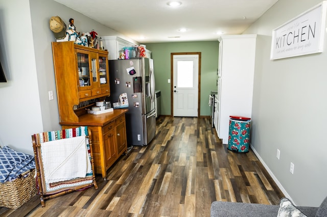 kitchen featuring brown cabinets, baseboards, dark wood finished floors, and stainless steel fridge with ice dispenser