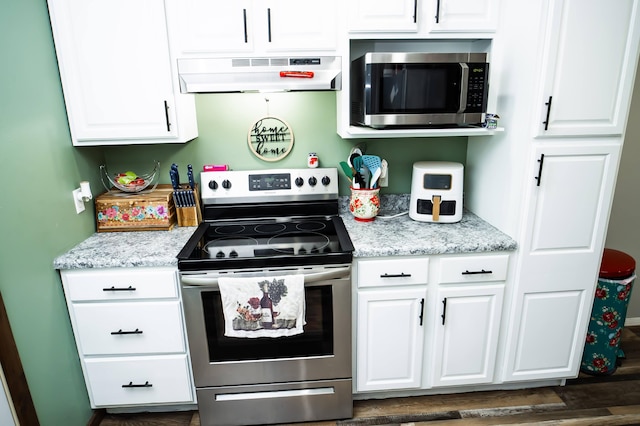 kitchen with under cabinet range hood, white cabinetry, stainless steel appliances, and dark wood-style flooring