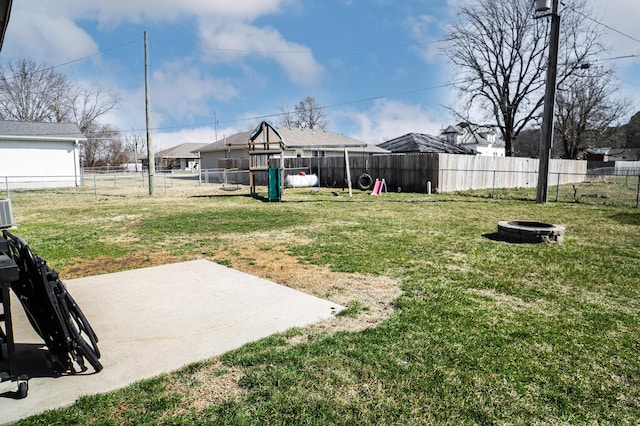 view of yard with a fire pit, a patio area, a fenced backyard, and a playground