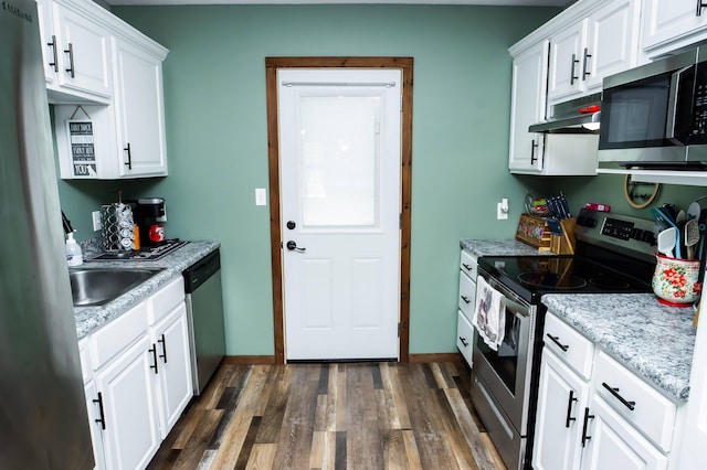 kitchen with under cabinet range hood, white cabinetry, baseboards, appliances with stainless steel finishes, and dark wood finished floors