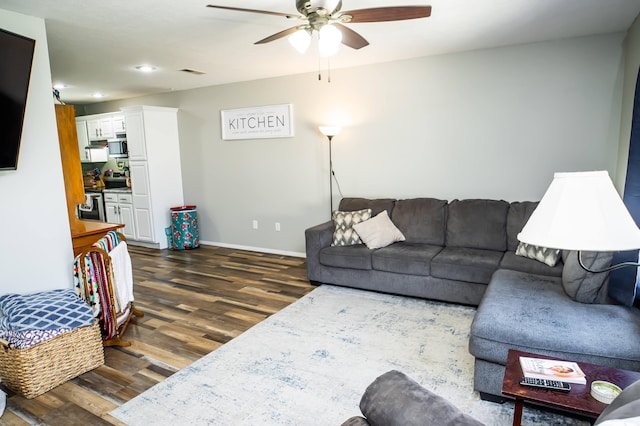 living room featuring ceiling fan, dark wood-type flooring, visible vents, and baseboards