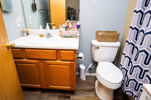 full bath with toilet, a shower with shower curtain, wood finished floors, and vanity