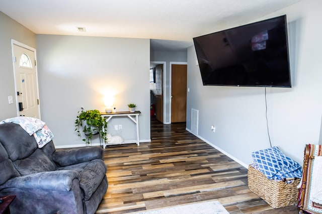 living room with wood finished floors, visible vents, and baseboards