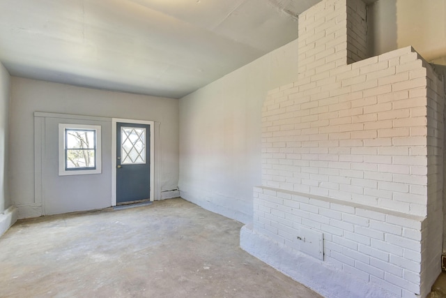 foyer entrance with brick wall and unfinished concrete floors