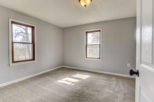 carpeted spare room featuring a textured ceiling and baseboards