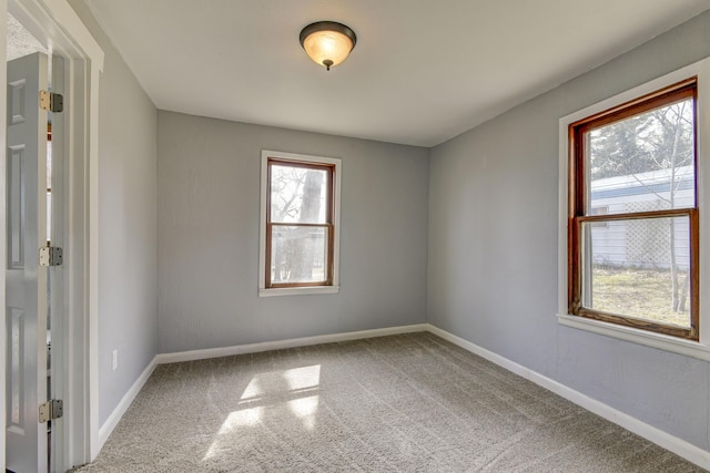 carpeted empty room featuring baseboards