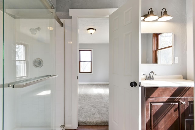 bathroom featuring baseboards, a shower stall, and vanity