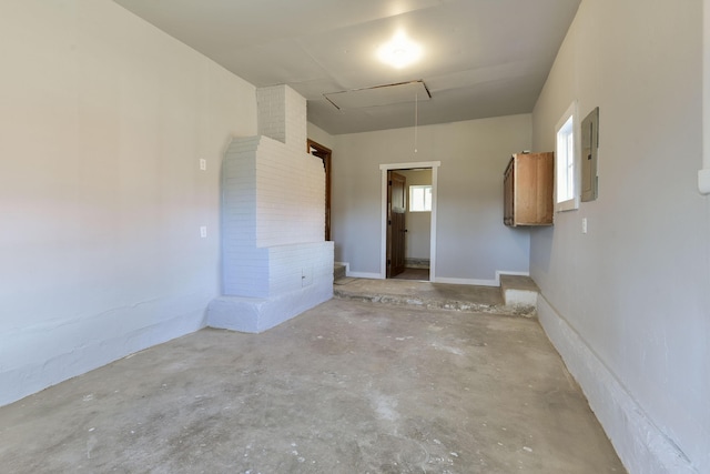 empty room featuring attic access, electric panel, and unfinished concrete floors