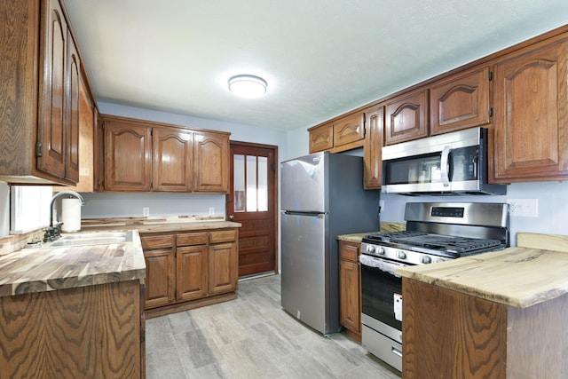 kitchen with appliances with stainless steel finishes, a sink, and brown cabinets