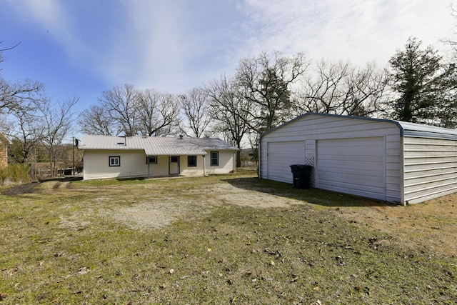 back of house with an outbuilding, metal roof, a lawn, and a garage