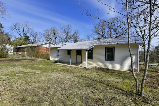 back of house featuring metal roof and a yard