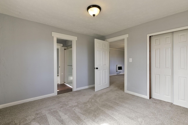 unfurnished bedroom with heating unit, carpet, baseboards, and a closet