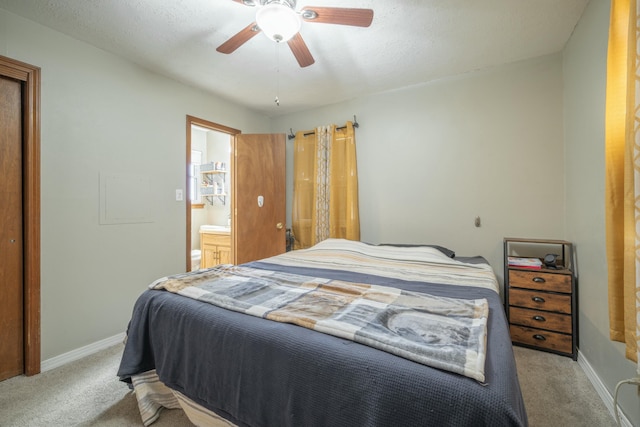 carpeted bedroom featuring a ceiling fan, connected bathroom, and baseboards