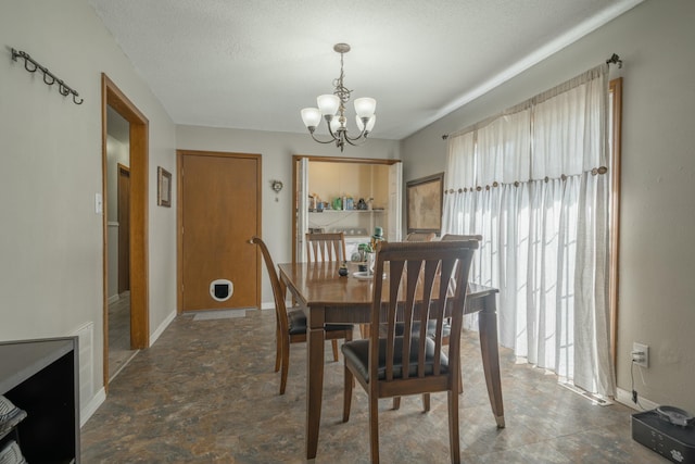 dining space with an inviting chandelier, stone finish flooring, baseboards, and a textured ceiling