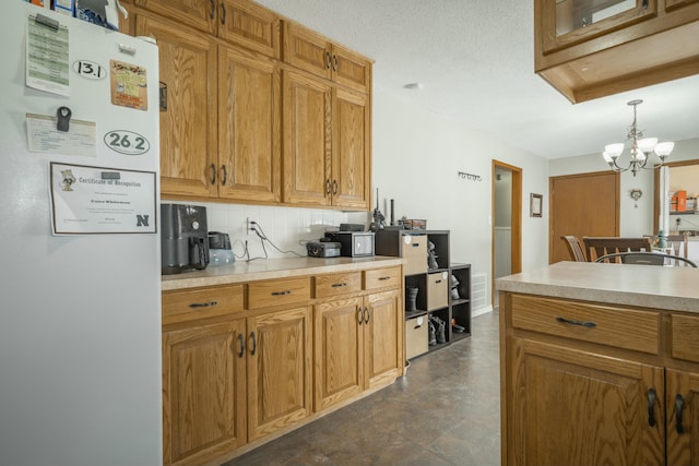 kitchen featuring brown cabinets, tasteful backsplash, light countertops, and freestanding refrigerator