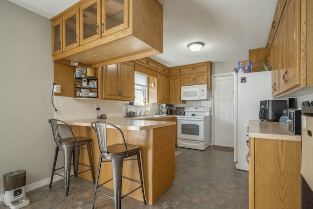 kitchen with white appliances, a breakfast bar, brown cabinets, a peninsula, and light countertops