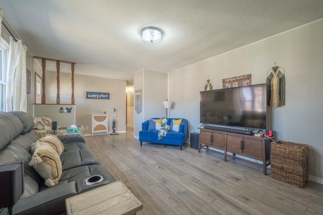 living room with a textured ceiling, baseboards, and wood finished floors