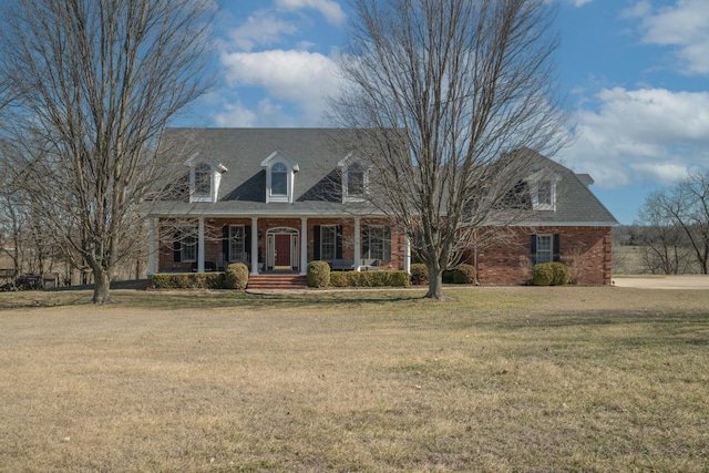 cape cod home with covered porch, a front yard, and brick siding