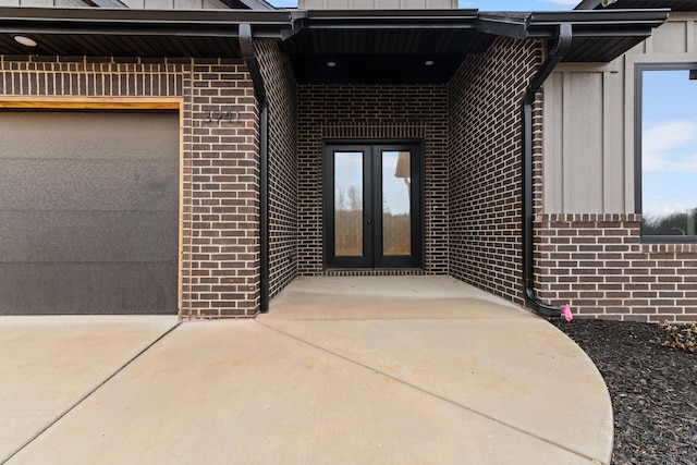 property entrance with a garage, brick siding, driveway, and french doors