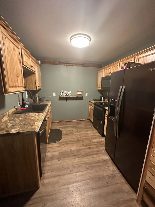 kitchen with black appliances, light wood-style flooring, a sink, and light brown cabinetry