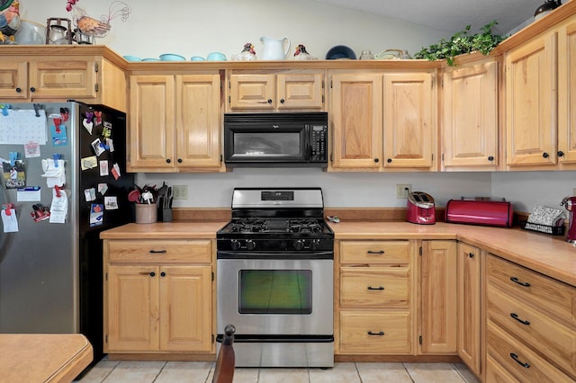 kitchen featuring lofted ceiling, light countertops, appliances with stainless steel finishes, and light brown cabinetry