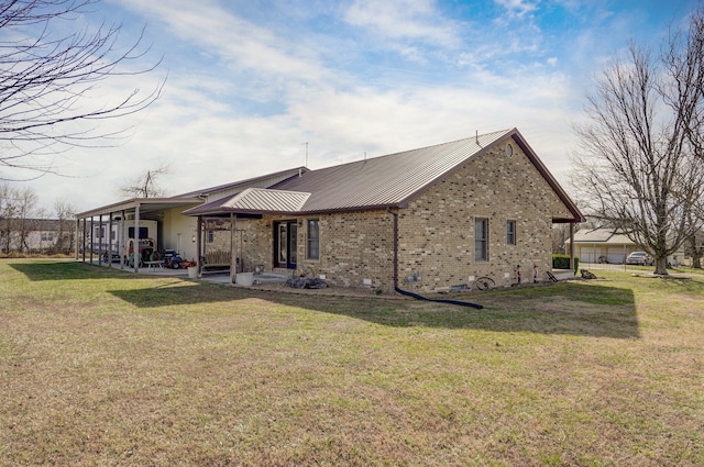 rear view of property featuring metal roof, brick siding, a lawn, crawl space, and a patio area