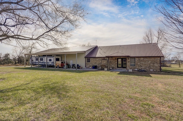 back of house featuring metal roof, brick siding, and a lawn