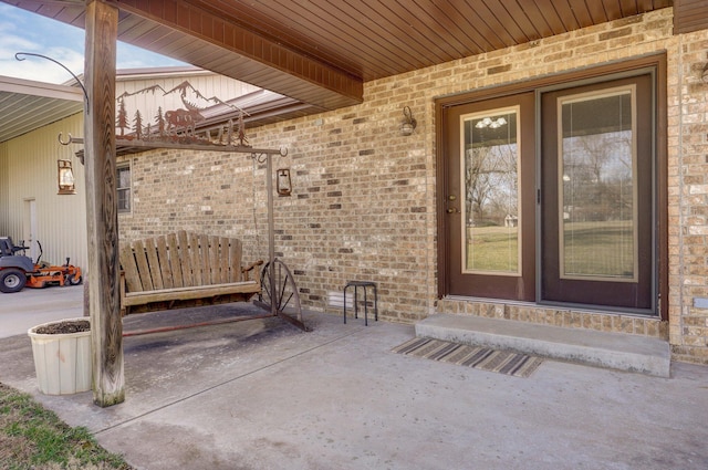 view of exterior entry featuring a patio and brick siding